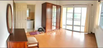 Spacious bedroom with wooden flooring and large windows opening to a balcony.