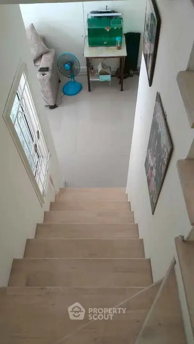 Cozy interior view with staircase leading to a living area featuring a sofa and fan.