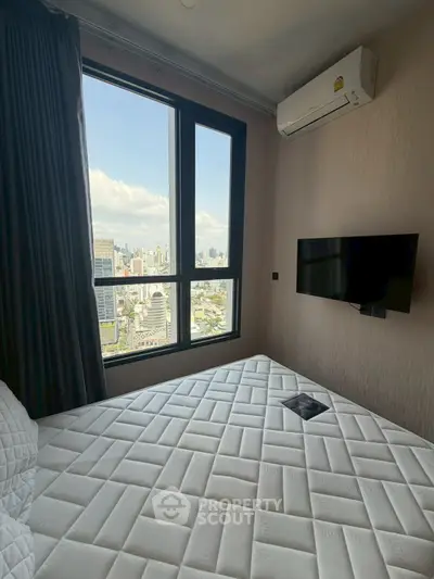 Modern bedroom with city view, air conditioning, and wall-mounted TV in high-rise apartment.