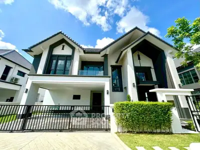 Stunning modern two-story house with sleek architecture and spacious driveway under a clear blue sky.