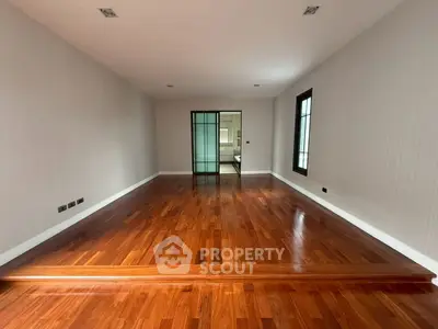 Spacious empty room with polished wooden floors and large windows