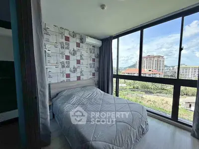 Modern bedroom with large windows offering a stunning city view in a high-rise apartment.