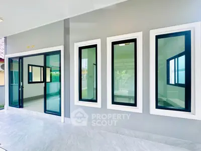 Modern home exterior with sleek glass windows and sliding door, showcasing contemporary architectural design.