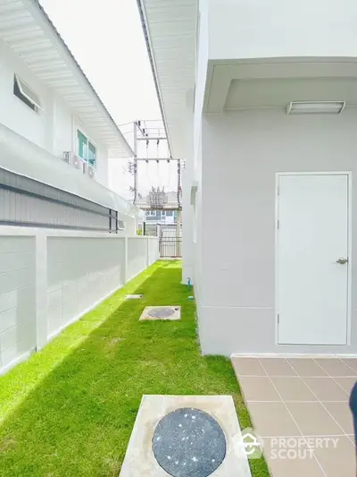 Modern exterior side view of a contemporary home with lush green lawn and sleek design.