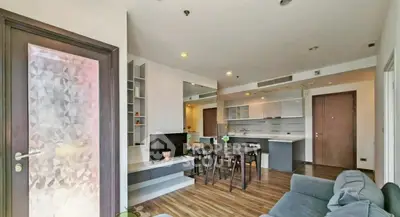 Modern open-plan living room with stylish decor and wooden flooring, featuring a cozy seating area and dining space.