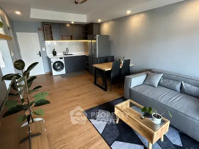 Modern living room with open kitchen, featuring sleek furniture and wooden flooring for a cozy ambiance.