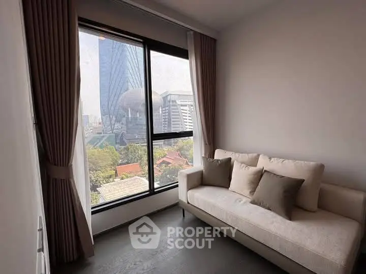 Cozy living room with city view through large window, featuring a comfortable sofa and elegant curtains.