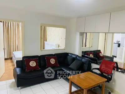Cozy living room with black leather sofa and wooden table, adjacent to bedroom.