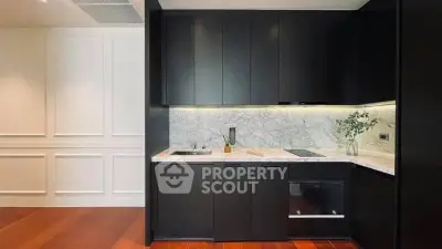 Modern kitchen with sleek black cabinetry and marble backsplash in luxury apartment.