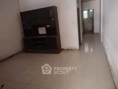 Spacious empty room with tiled floor and wooden cabinet, ideal for customization.