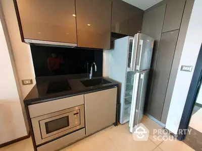 Sleek modern kitchen with built-in appliances and ample storage, featuring a stainless steel refrigerator and an integrated oven.