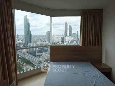 Stunning bedroom with panoramic city view in a high-rise apartment, featuring large windows and modern decor.