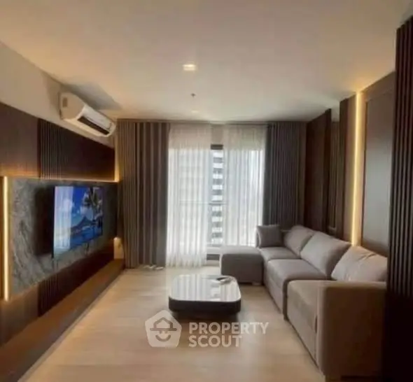 Modern living room with sleek design and large sofa, featuring a wall-mounted TV and stylish lighting.