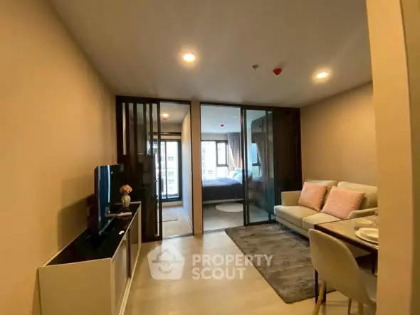 Modern living room with cozy sofa and TV, leading to a bright bedroom.