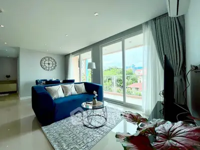 Luxurious living room with plush blue sofa and large windows offering a scenic view.