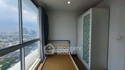 Compact bedroom with city view, single bed, and wardrobe in modern apartment.