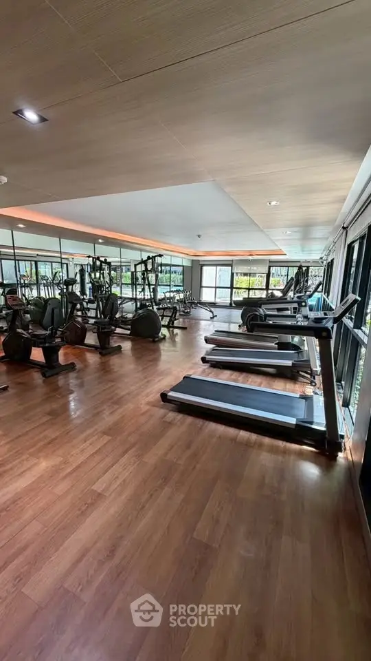 Spacious modern gym with state-of-the-art equipment and large windows for natural light.