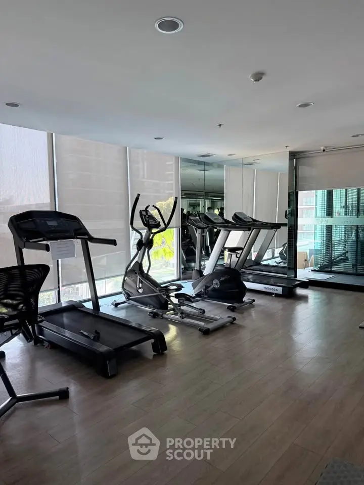 Modern gym with state-of-the-art equipment and large windows in a luxury residential building.