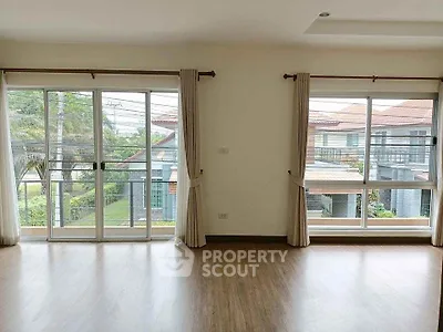 Spacious living room with large windows and wooden flooring in modern home.