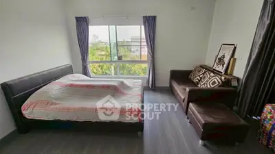 Spacious bedroom with large window and cozy seating area, offering serene views and modern comfort.