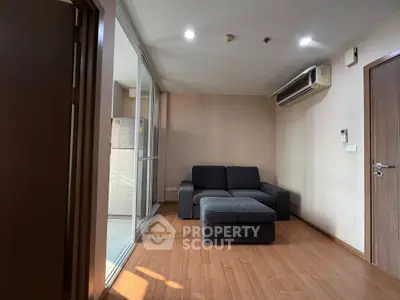 Cozy living room with modern sofa and wooden flooring, featuring a split air conditioning unit.