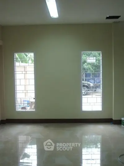 Spacious room with large windows and glossy tiled floor, ideal for natural light and modern living.