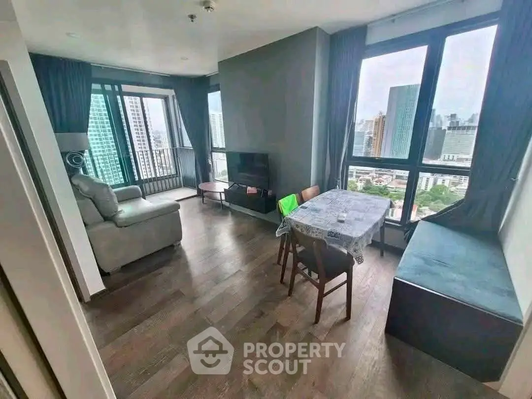 Modern living room with city view, featuring hardwood floors and stylish furniture in a high-rise apartment.