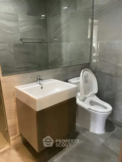 Modern bathroom with sleek design featuring a square sink and contemporary toilet.