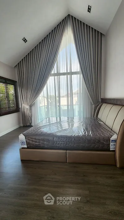 Luxurious bedroom with high ceiling and elegant drapes, featuring a modern bed and large window.