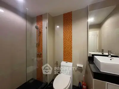 Modern bathroom with sleek fixtures and stylish orange tile accent wall.