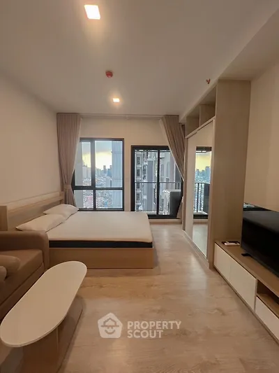 Modern bedroom with city view and balcony access in high-rise apartment