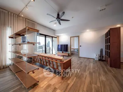 Spacious modern living room with wooden flooring and large windows offering city views.