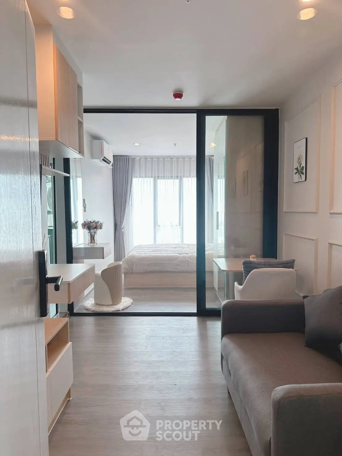 Modern apartment interior with open living room and bedroom, featuring sleek design and natural light.