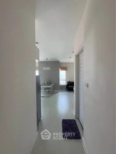 Modern apartment hallway leading to bright living area with dining set and city view.