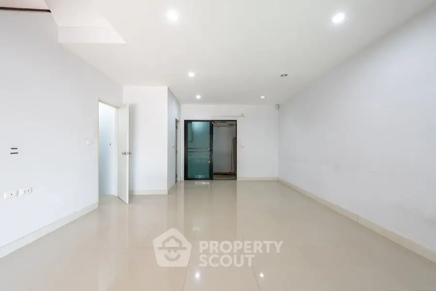 Spacious empty room with glossy tiled flooring and bright lighting.