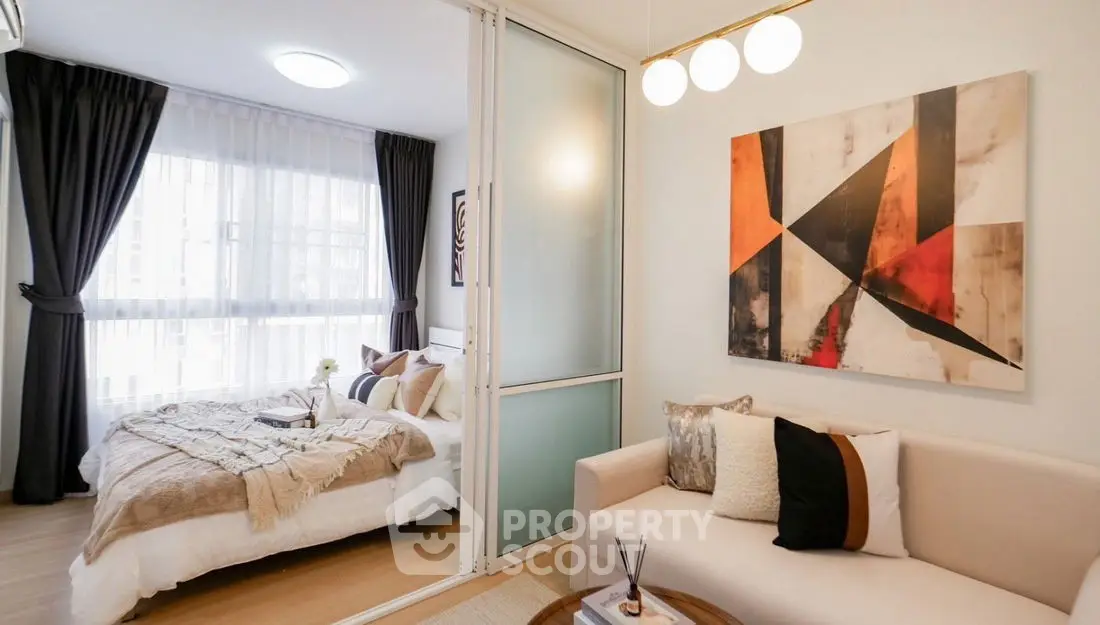 Modern studio apartment with cozy living area and stylish bedroom separated by glass partition.