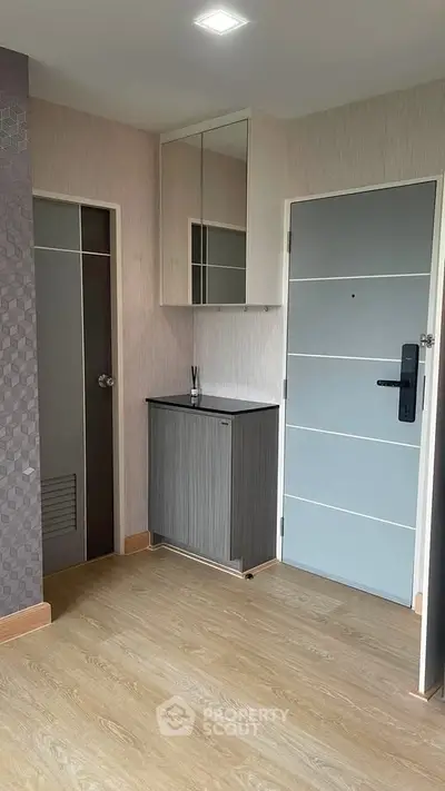 Modern apartment entrance with sleek wooden flooring and stylish cabinetry.