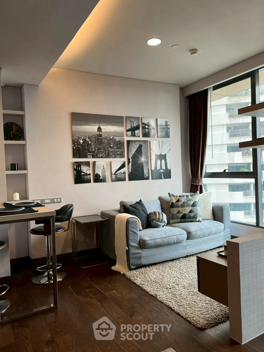 Modern living room with stylish decor and large windows offering city views.