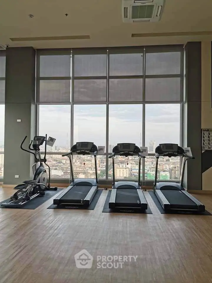 Spacious gym with modern equipment and panoramic city view, perfect for fitness enthusiasts.