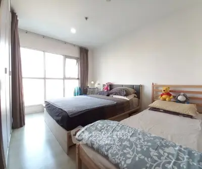Spacious bedroom with two beds and large window offering natural light.