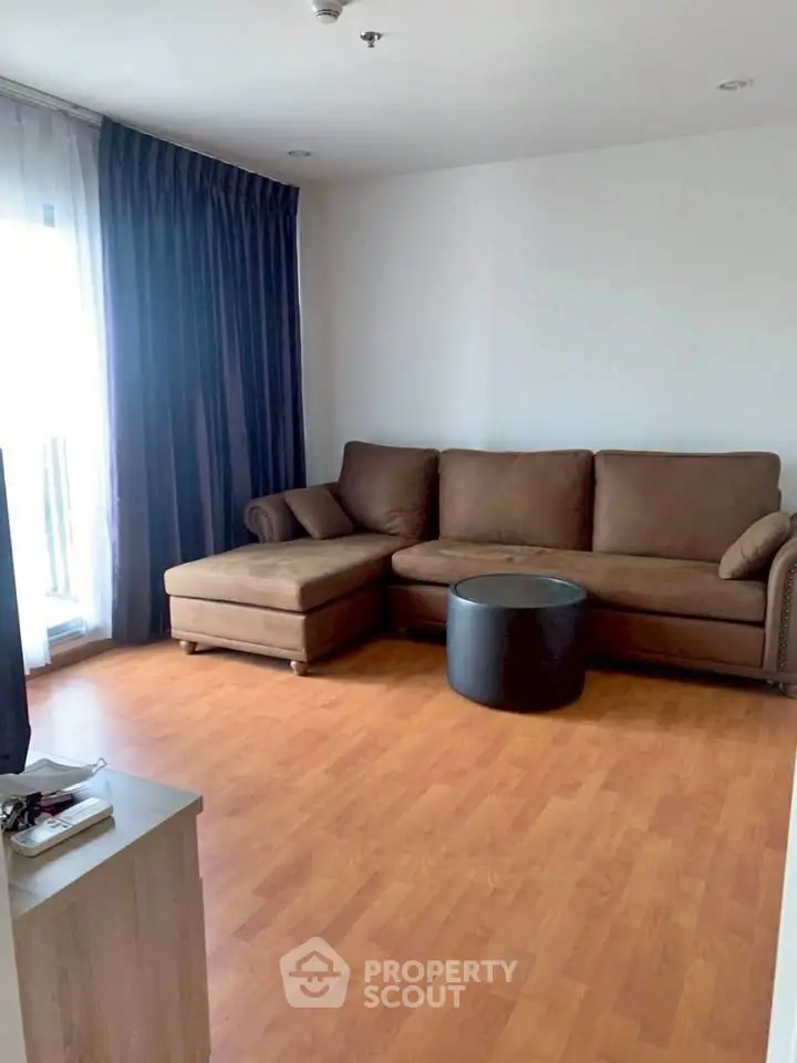 Spacious living room with brown sectional sofa and natural light from large window.