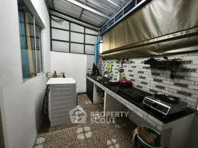 Compact kitchen with washing machine and gas stove in a cozy home setting.