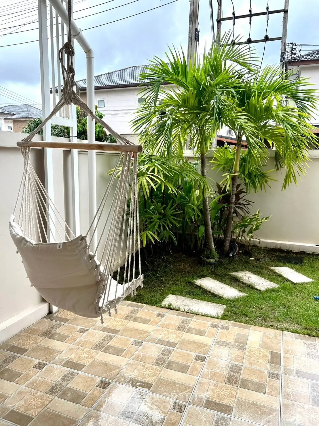 Charming patio with hammock and lush garden view, perfect for relaxation.