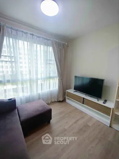 Bright living room with large window and modern TV setup