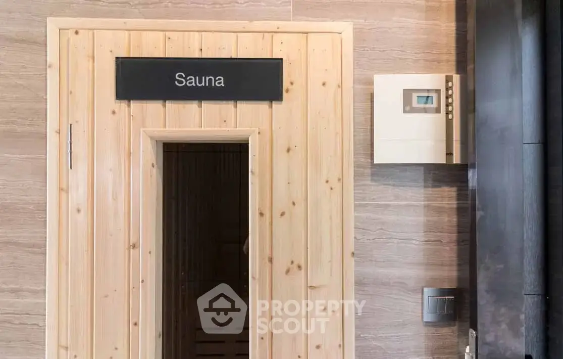 Luxurious sauna entrance in modern building with wooden door and control panel.