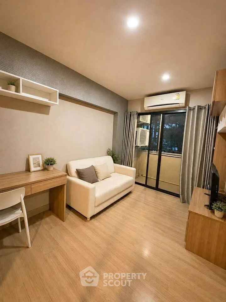 Modern living room with cozy sofa, desk, and balcony access in a stylish apartment.