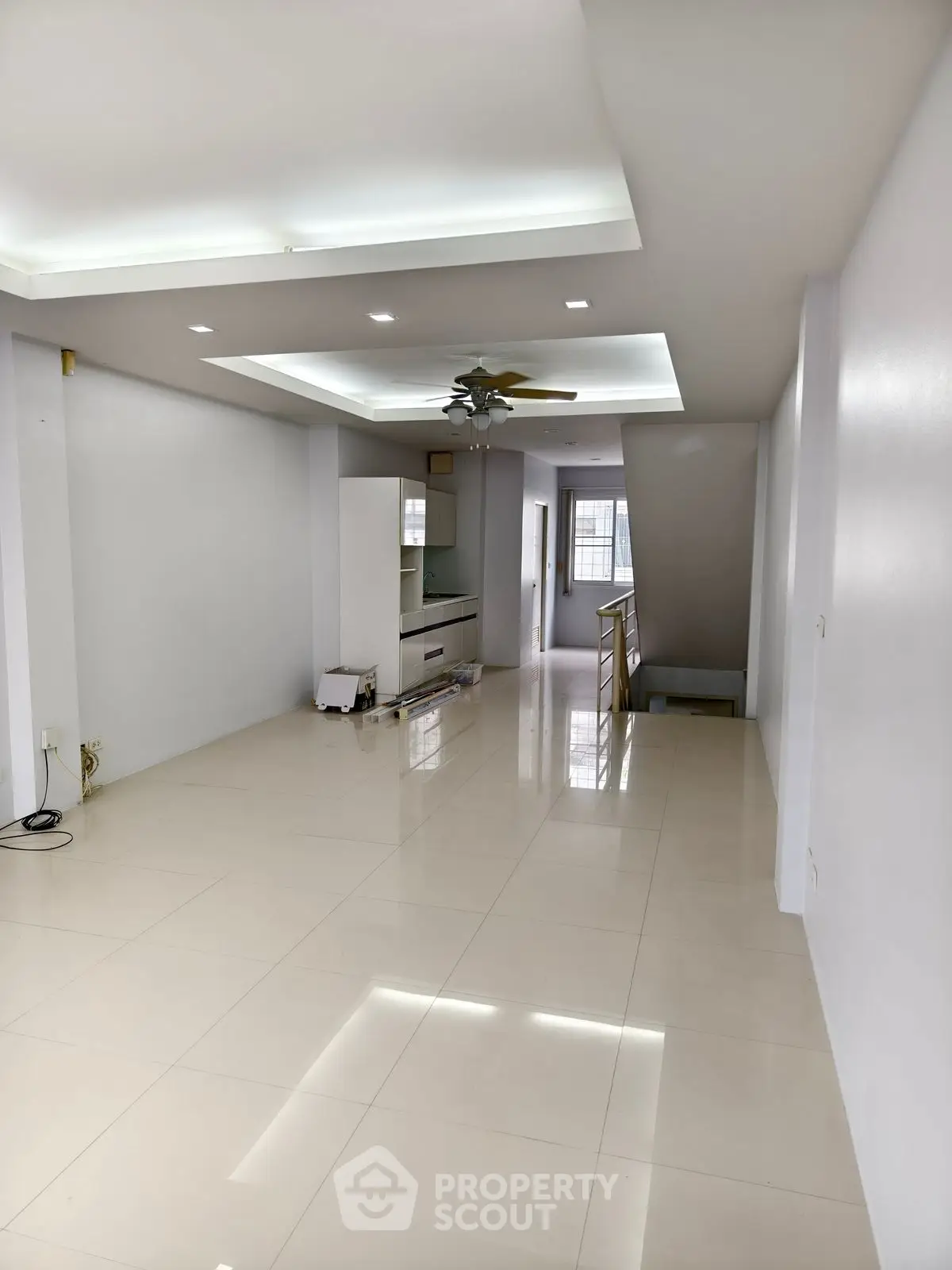 Spacious modern living room with sleek tile flooring and ceiling fan, ideal for family gatherings.