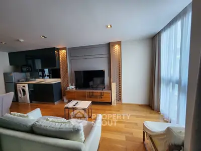 Modern living room with open kitchen, featuring sleek appliances and stylish decor.