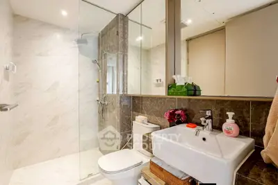 Modern bathroom with glass shower, sleek fixtures, and elegant marble tiles.