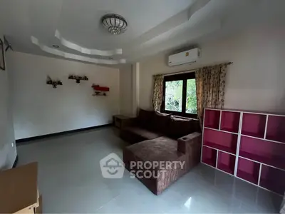 Spacious living room with modern sofa and air conditioning, ideal for relaxation.